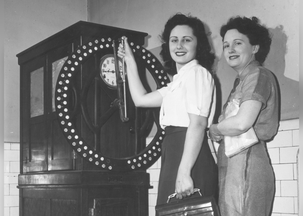 Two women at dial recorder time clock