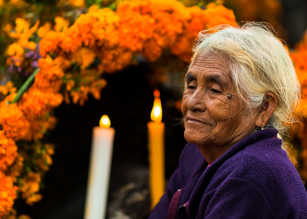 A Mixtec indigenous woman sits on the flower-decorated grave at a cemetery during the Day of the Dead celebrations.