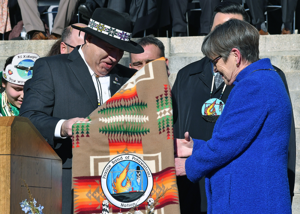 Kansas governor Laura Kelly is presented with a ceremonial blanket by members of the Prairie Band Of The Potawatomi Nation.