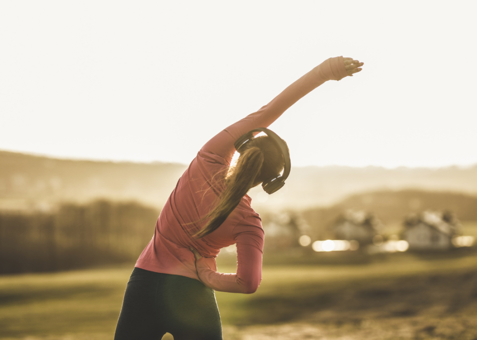 Female jogger stretches in front of scenic morning landscape