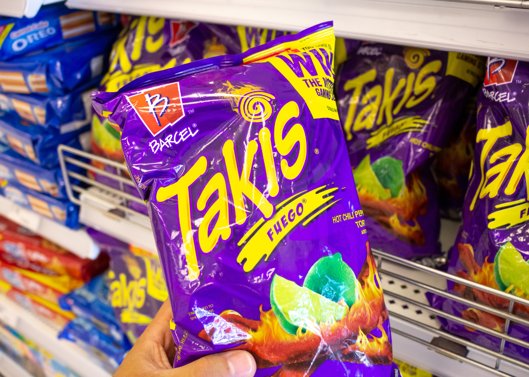 Hand holding package of Takis in supermarket.