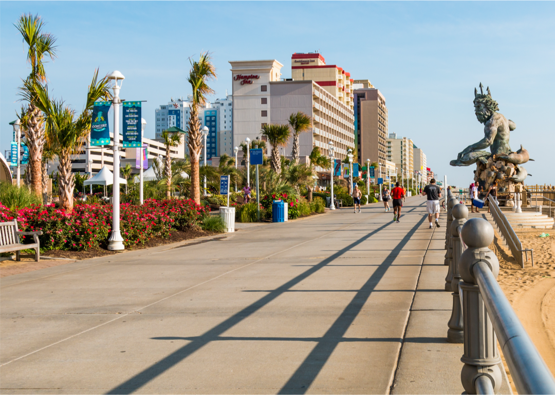 People walk along the oceanfront boardwalk and resort area in Virginia Beach.