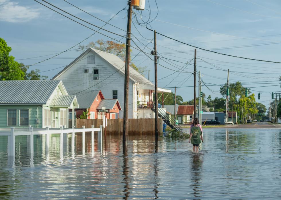 Photo shows a flooded neighborhood with water rising into the first floor of many homes and at knee-level for passers-by