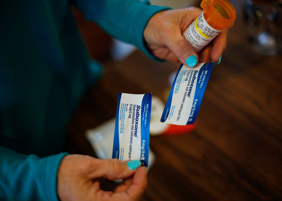 Person holding two small packages of Suboxone and a pill bottle.