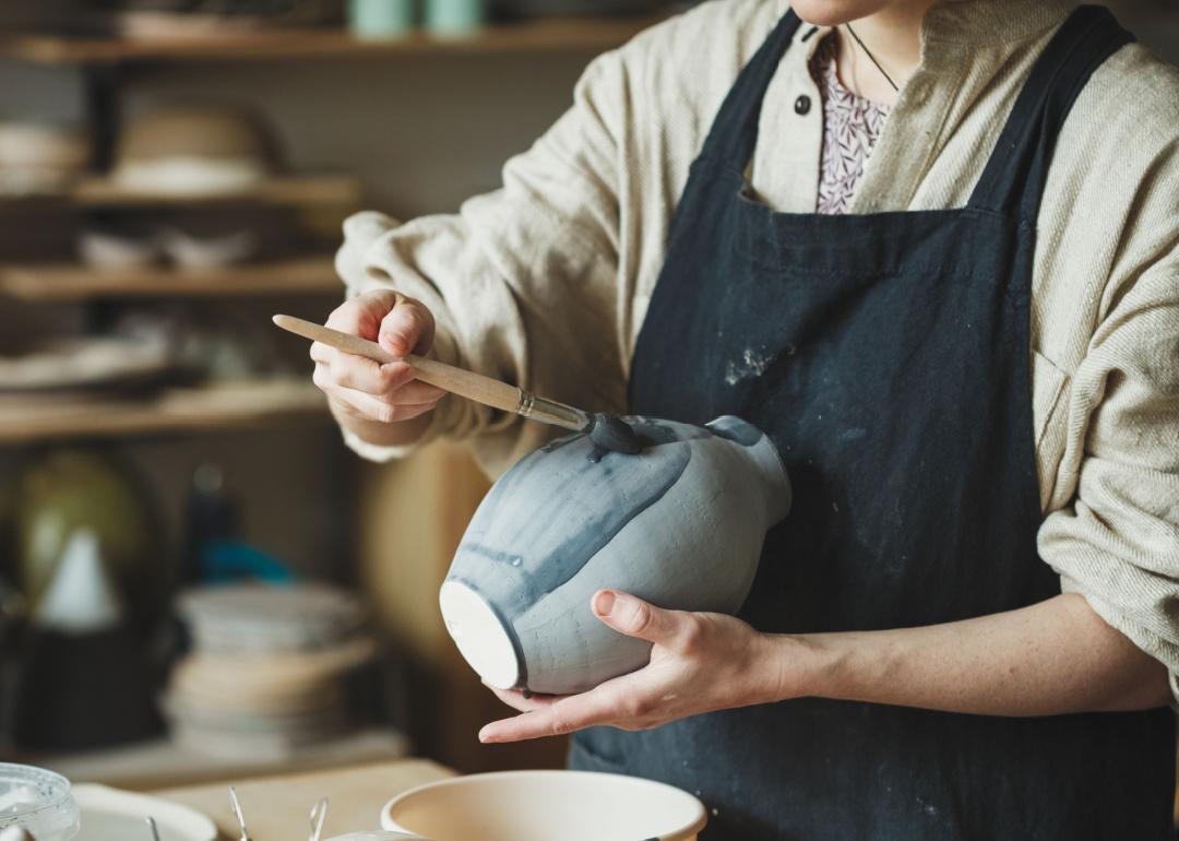Potter adding colored glaze to a ceramic vase.