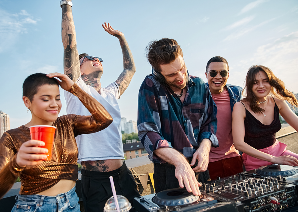 Friends dancing around dj table on rooftop.