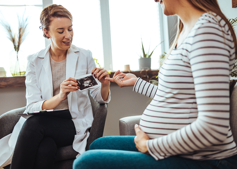 Midwife nurse talking to pregnant patient.