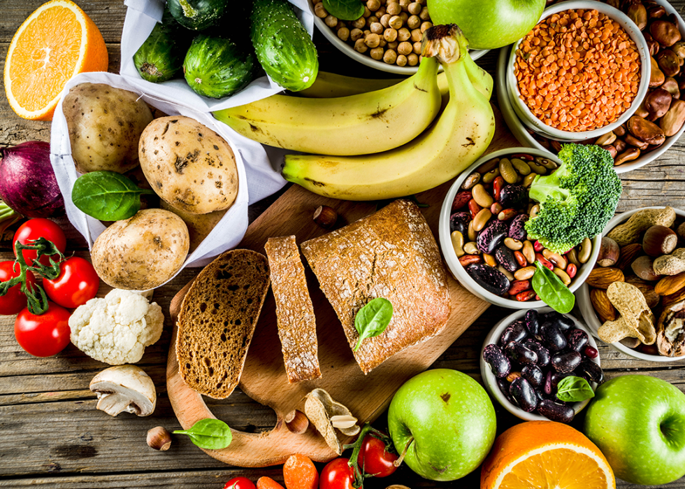 Selection of fruits, vegetables, cereals, brown bread, legumes, nuts, and greens.