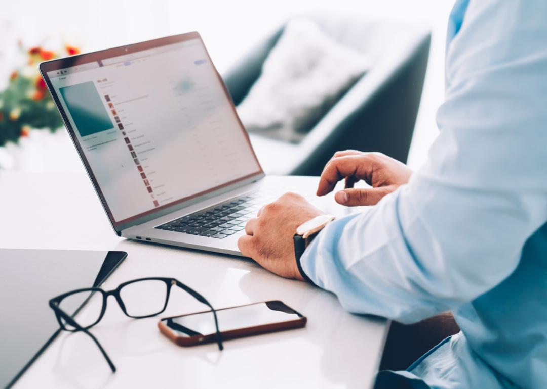 Person composing email on laptop computer in office.