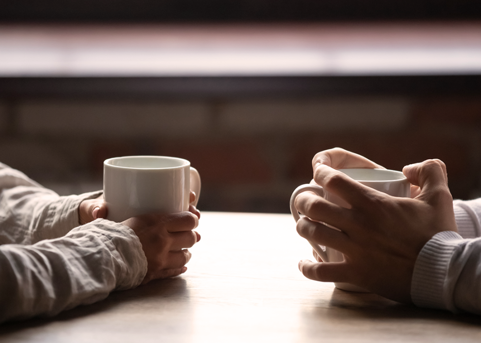 Close up two people with coffee cups.