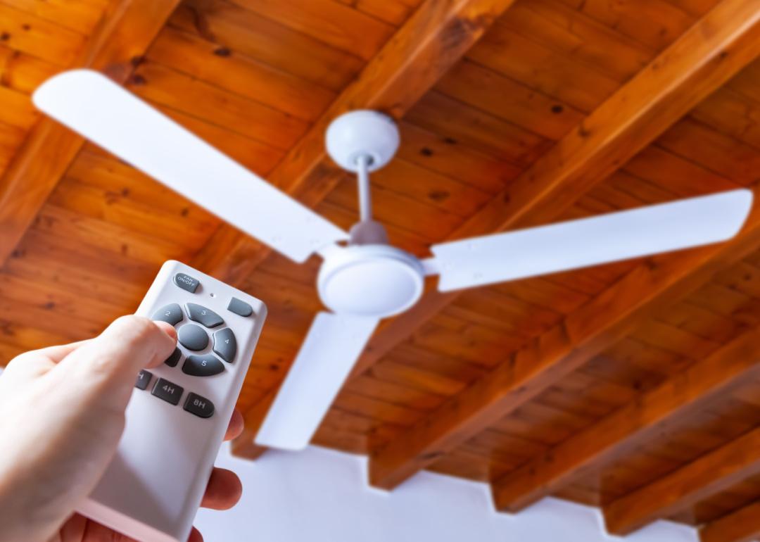 A person using a remote control to operate a ceiling fan.