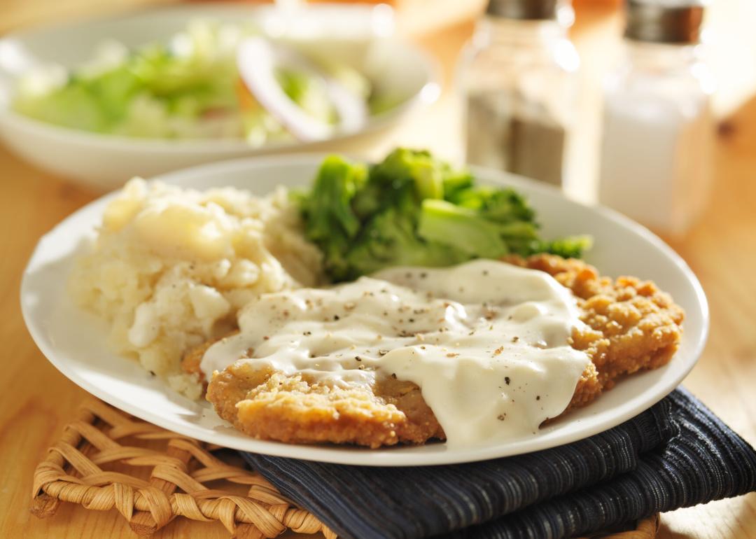 Plate with country fried steak with gravy, mashed potatoes, and broccoli.