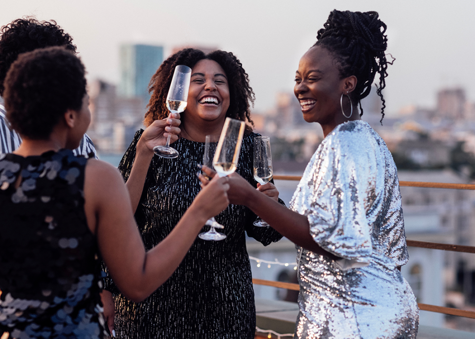 Friends toast champagne glasses on rooftop.