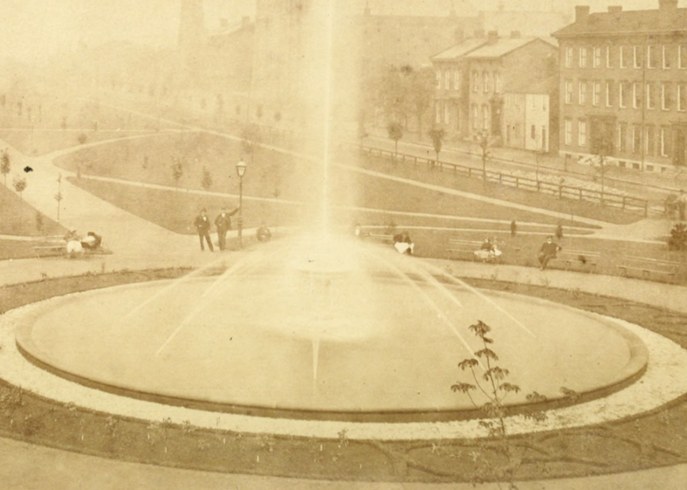 People sitting on benches by large fountain