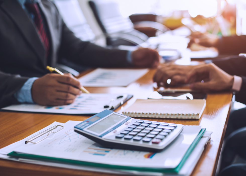 Cropped view of professionals reviewing paperwork with calculator.