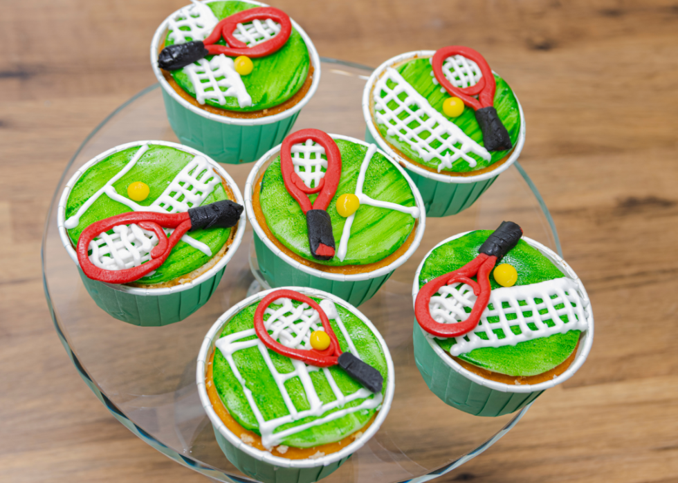 Six tennis-themed cupcakes on a plate. 