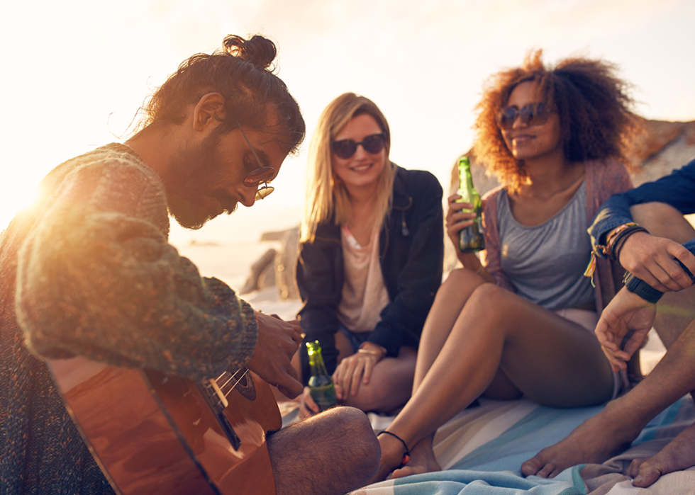 Friends playing guitar on beach.