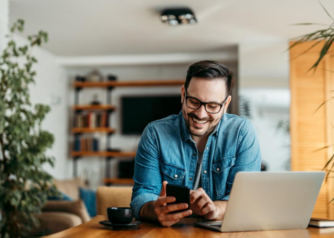 Cheerful man using phone at home