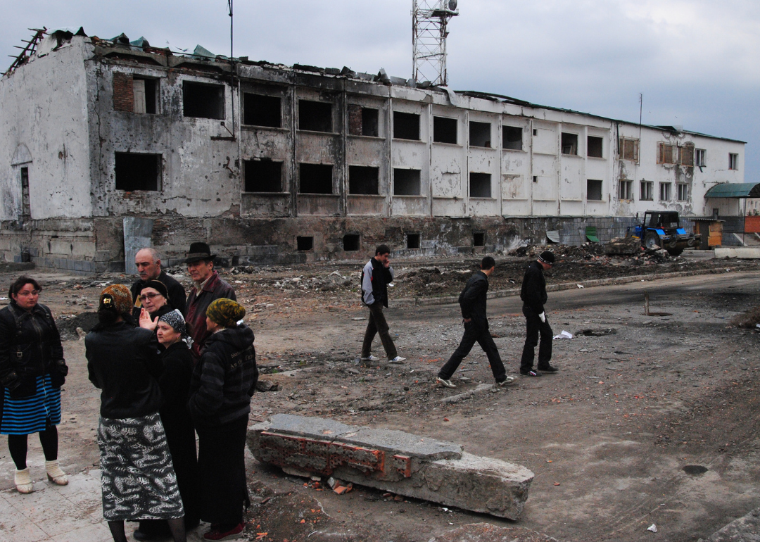 Ingush people talking near remains of bombed police compound.