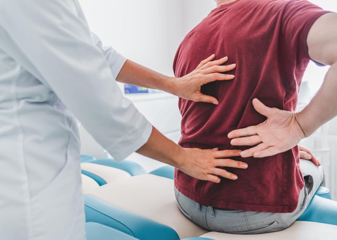 Orthopedist examining patient's back in clinic.