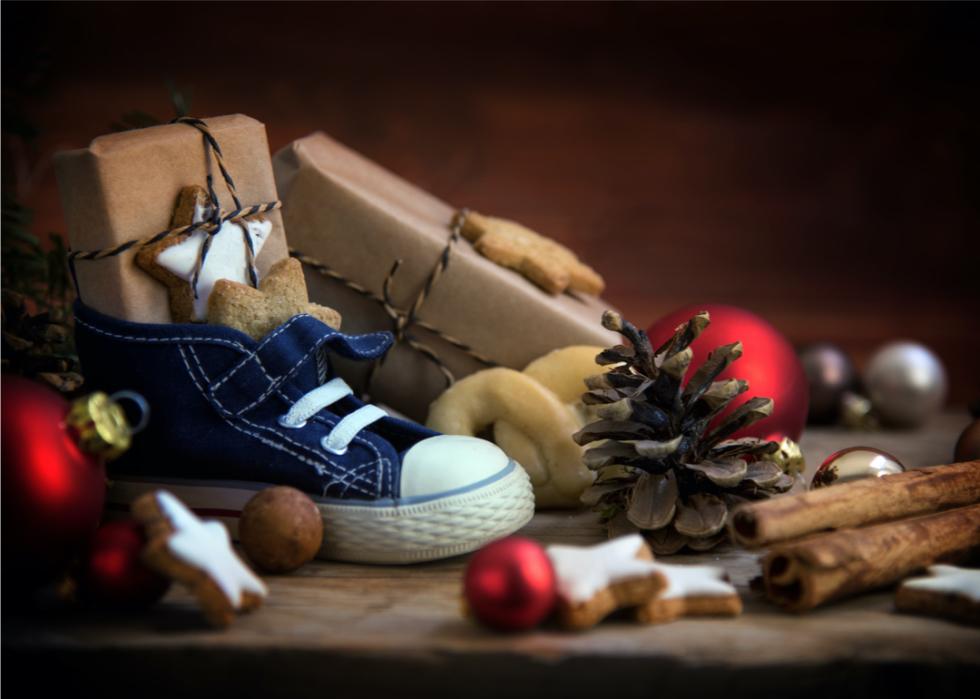 A close up of a child's shoe filled with a brown paper wrapped box and star shaped cookies.