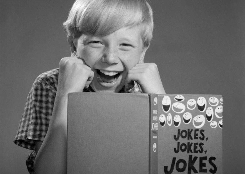 Boy laughing at joke book.