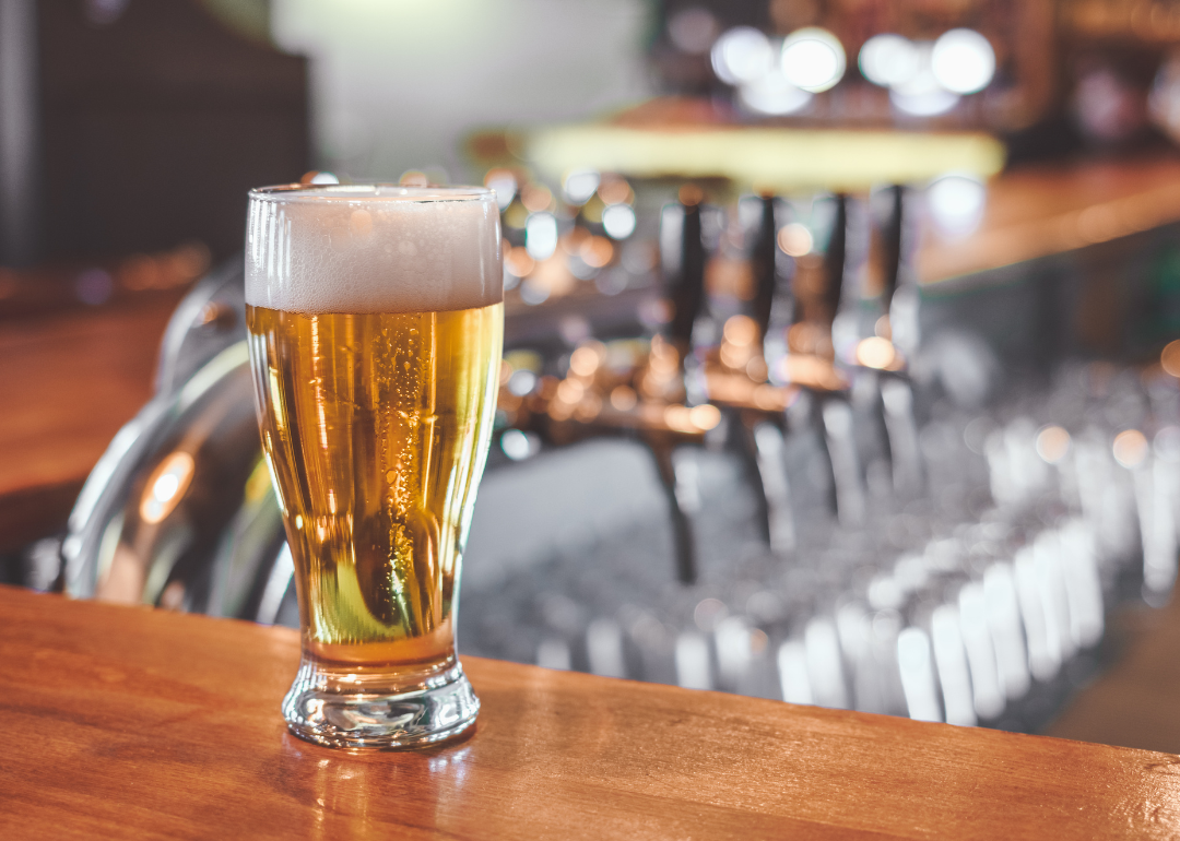 A beer glass of pale ale sitting on a bar.