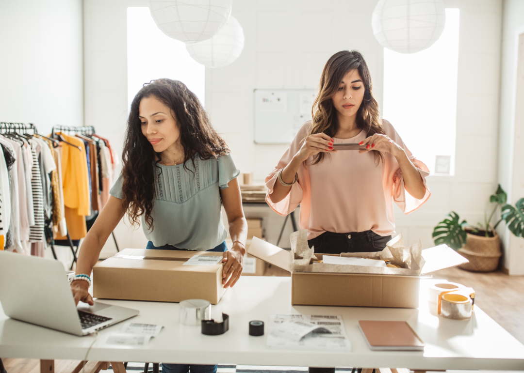 Two small business owners packing and shipping apparel in shop.