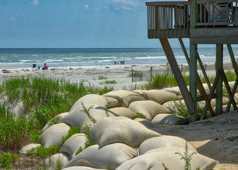 Photo shows a wall of sand bags protecting a coastal home
