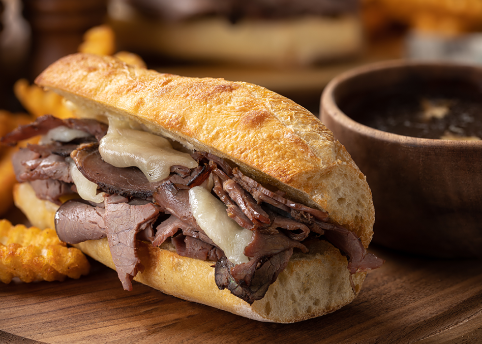 French dip sandwich and french fries with bowl of au jus in background.