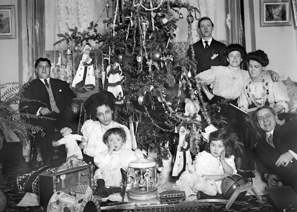 An extended family poses around the tree on Christmas morning with all their opened gifts.