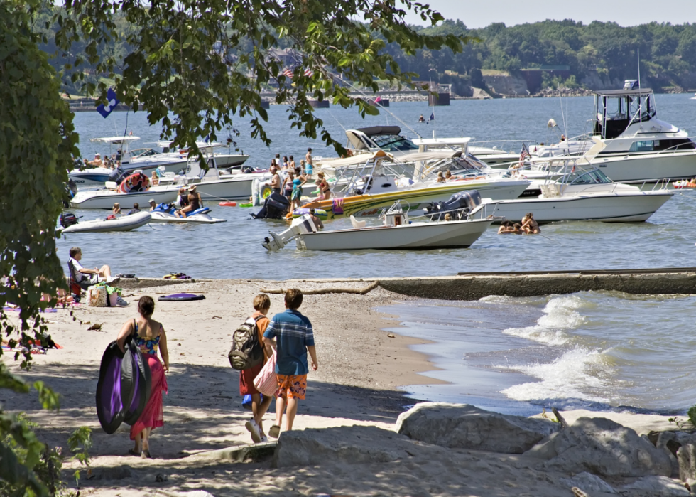 People walking along Lake Erie beach by boats