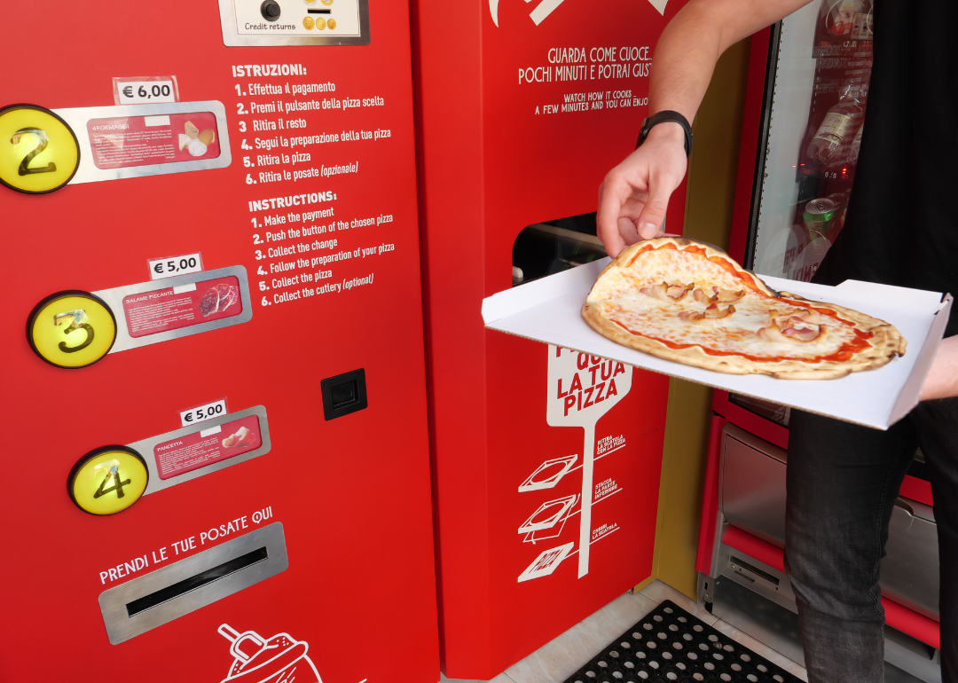 Person removing pizza from vending machine.