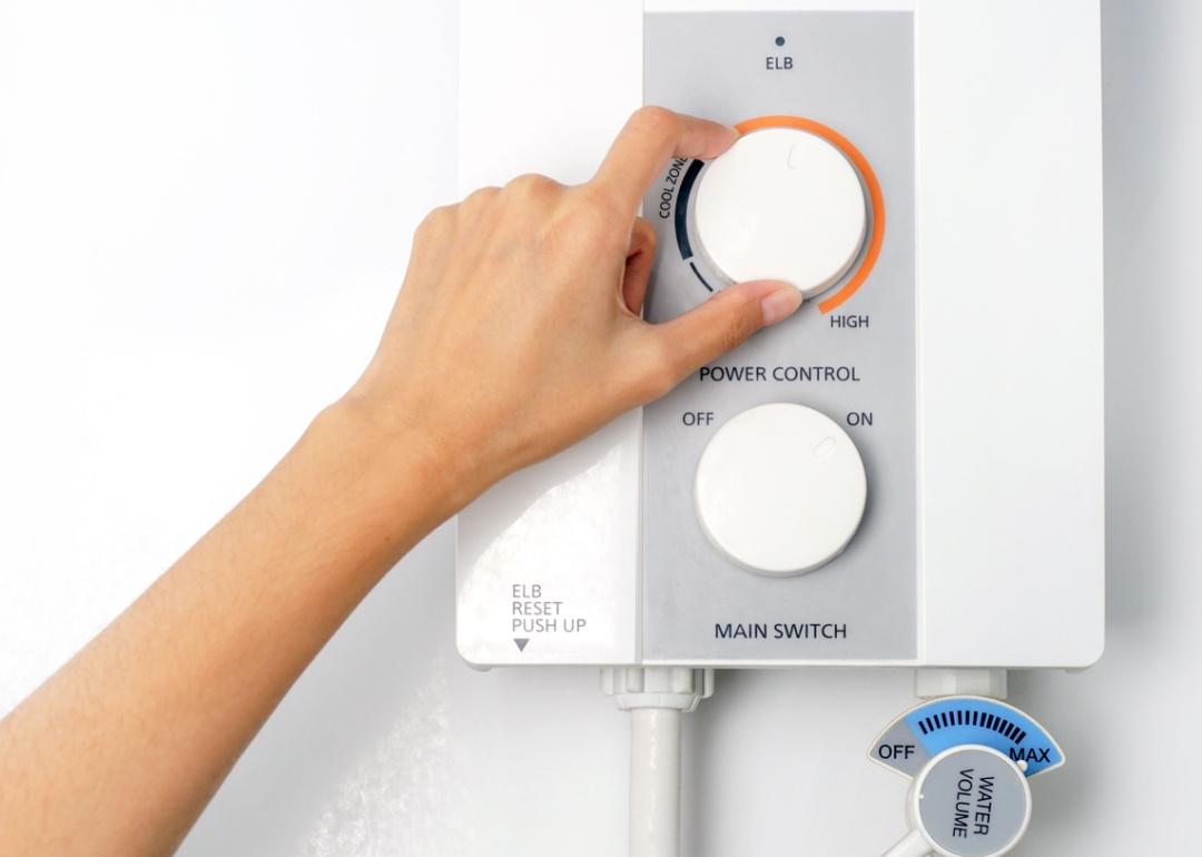 Hand adjusting temperature of water heater.