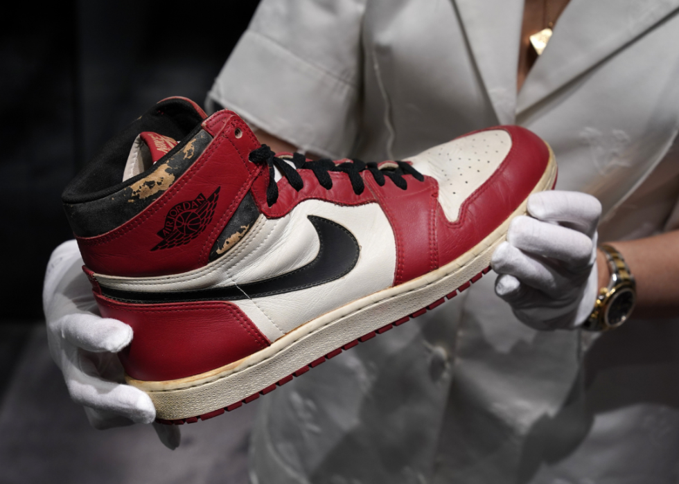 White gloved hands hold a Air Jordan 1 High Top sneaker at Christie’s.
