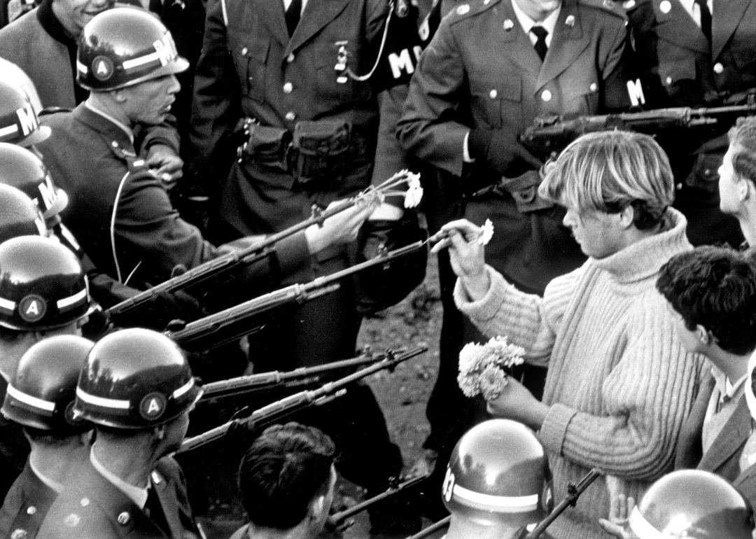 Antiwar demonstrators put flowers in MP gun barrels at Pentagon.