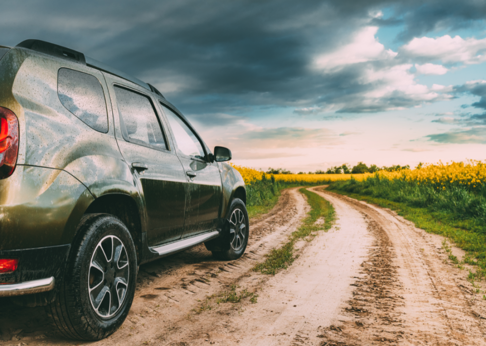 A green SUV on a country road.