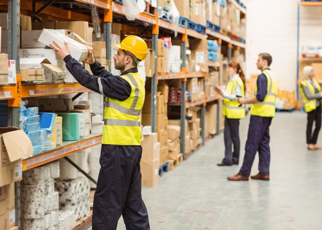 Workers moving packages to shelves in warehouse.