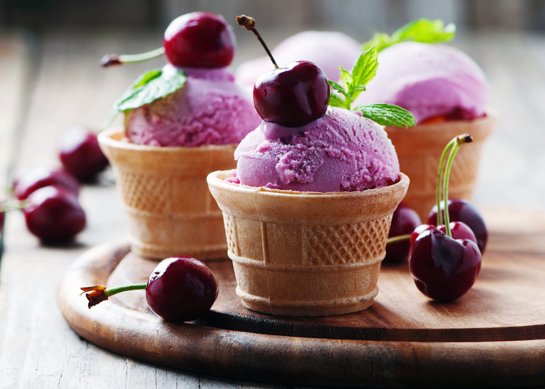 Cone cups of cherry ice cream with fresh cherries.