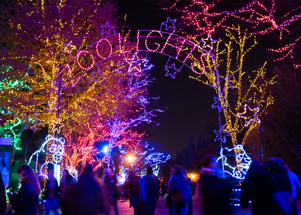 People walk under the Zoo Lights archway at night.