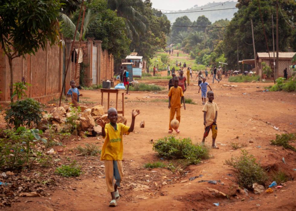 Group of children playing soccer on a rural road