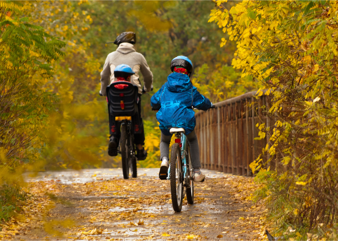 Family on bicycles in park on fall day.