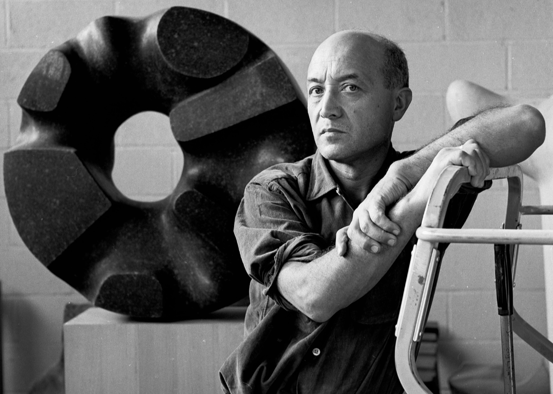 Isamu Noguchi poses with sculptures in his studio.