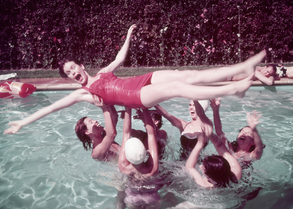 A group of women lift another woman out of the water during a photo shoot for swimwear designer Rose Marie Reid.