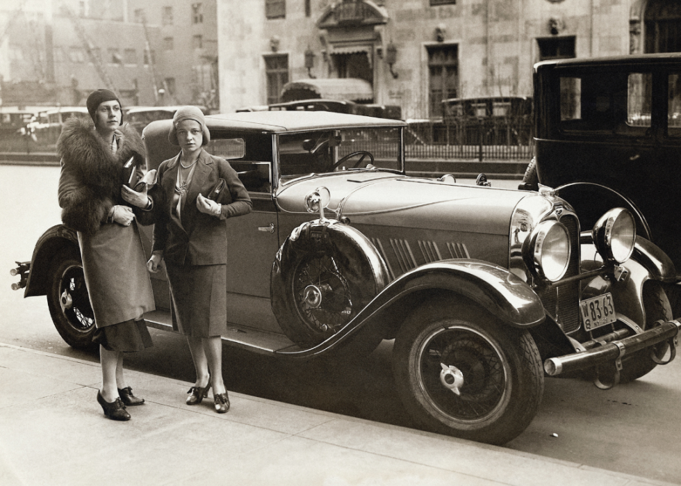 Two women stand beside car