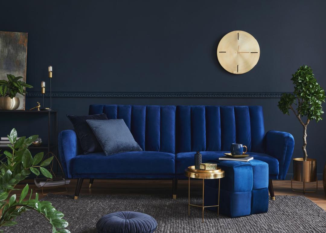 Modern living room with blue velvet sofa and gold accents.