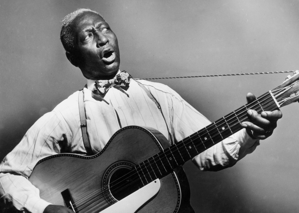 Huddie 'Leadbelly' Ledbetter playing a 12-string guitar and singing.