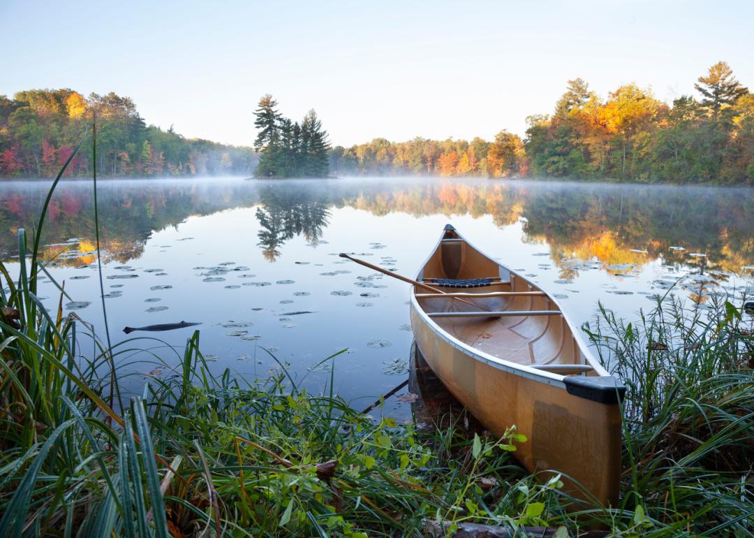 Canoe on lake at sunrise in autumn.