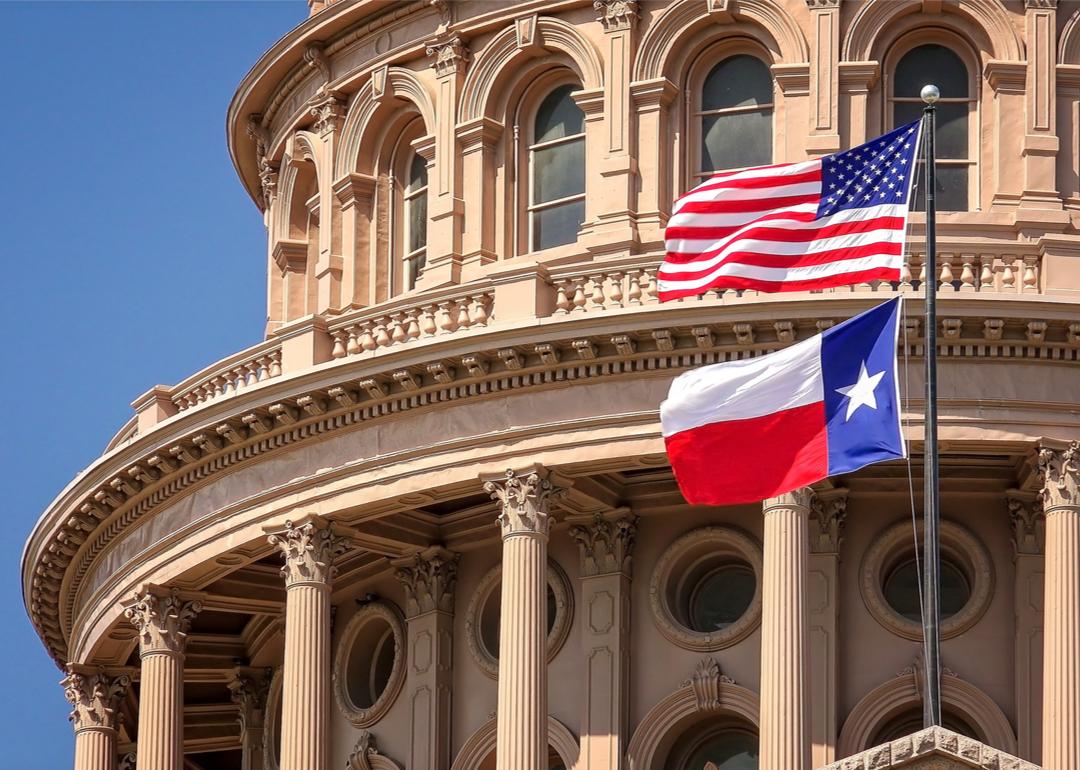 Flags flying in front of the Texas Capitol dome.