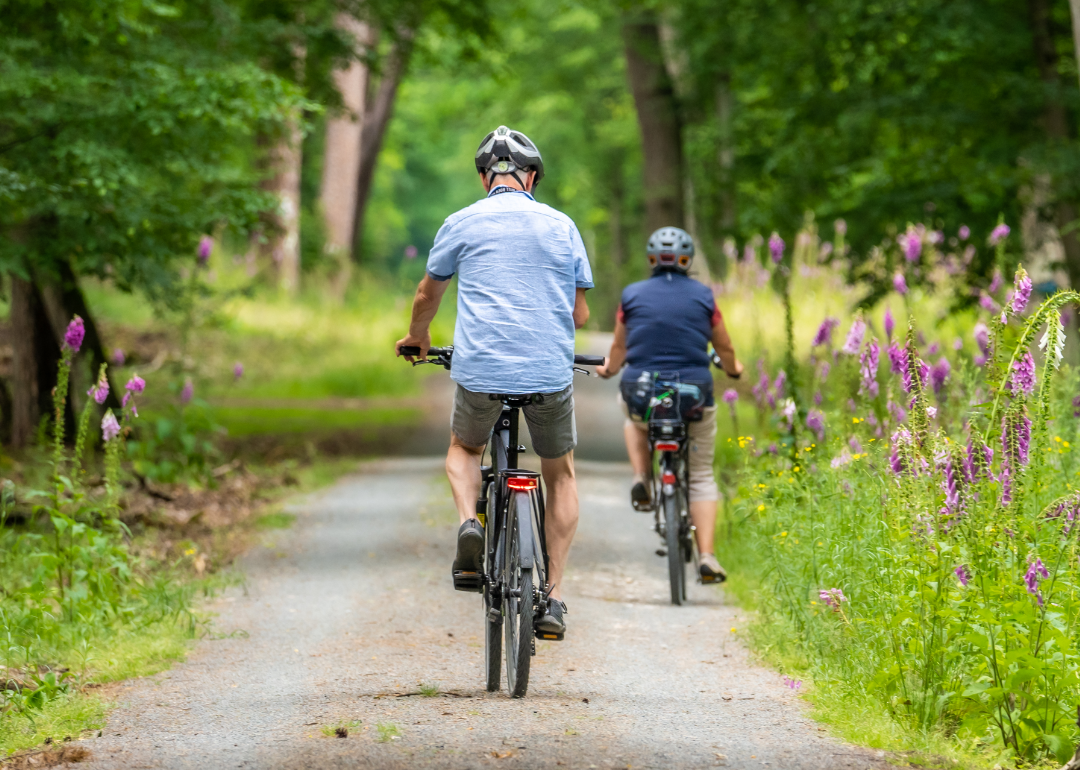 Two people riding bicycle on trail.